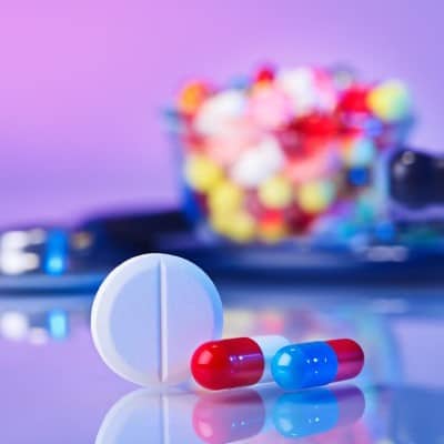 A large white tablet and two pill capsules in the foreground